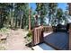 Backyard featuring a wooden deck leading to a landscaped garden with a walkway and surrounding treelined forest at 8171 S Homesteader Dr, Morrison, CO 80465