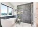 Modern bathroom featuring a soaking tub, walk-in shower with elegant tile, and a large window with a scenic view at 8171 S Homesteader Dr, Morrison, CO 80465