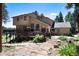 Multi-level home with deck, surrounded by lush landscaping and trees, with stone steps leading up to the house at 8171 S Homesteader Dr, Morrison, CO 80465
