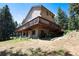 Back exterior view of home with large deck, lush trees, and natural landscaping at 8171 S Homesteader Dr, Morrison, CO 80465