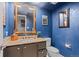 Stylish powder room featuring blue walls, decorative artwork, and a framed mirror at 7201 E Quincy Ave # 102, Denver, CO 80237