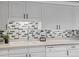 Bright and modern kitchen with white cabinets and decorative backsplash at 7201 E Quincy Ave # 102, Denver, CO 80237