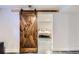 A view through a sliding barn door into a neutral-toned, modern basement bedroom at 3138 N Josephine St, Denver, CO 80205