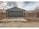 A gray detached garage featuring a traditional sectional garage door and horizontal wood fencing on each side at 3138 N Josephine St, Denver, CO 80205