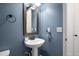 Stylish powder room featuring a pedestal sink, framed mirror, and modern fixtures at 3061 Low Meadow Blvd, Castle Rock, CO 80109