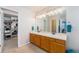 Bathroom boasts double sinks, large mirror with decorative lighting, and an organized walk-in closet at 5224 Snow Goose St, Brighton, CO 80601