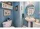 Cozy powder bathroom with blue paint, pedestal sink, framed mirror, and toilet at 5224 Snow Goose St, Brighton, CO 80601