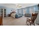 Spacious primary bedroom with blue walls, ceiling fan, windows, and rocking chair at 5224 Snow Goose St, Brighton, CO 80601