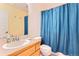 Well-lit bathroom with a wood vanity, blue shower curtain, and standard toilet at 511 Noel Ave, Longmont, CO 80501