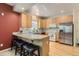 Bright kitchen with stainless steel refrigerator, breakfast bar and light wood cabinets at 511 Noel Ave, Longmont, CO 80501