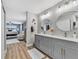 Modern bathroom with gray double vanity and marble countertop, dual round mirrors, and wood-look flooring at 15592 E Kenyon Ave, Aurora, CO 80013