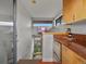 Compact kitchen adjacent to stairs with stainless steel appliances and warm wood cabinets at 1880 W 32Nd Ave, Denver, CO 80211