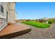 View of the fenced backyard with a small wooden deck, gravel and healthy green grass at 5779 Piney River Pl, Brighton, CO 80601
