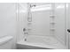 Clean white bathroom featuring a tiled tub with a shower head and a window for natural light at 5779 Piney River Pl, Brighton, CO 80601