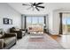 Bright living room with hardwood floors, large windows, and a modern ceiling fan at 5779 Piney River Pl, Brighton, CO 80601