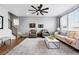 Open-concept living room with hardwood floors, natural light, and modern furnishings at 5779 Piney River Pl, Brighton, CO 80601