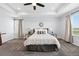 Bright main bedroom featuring tray ceiling, ceiling fan, soft carpet, and windows with natural light at 5779 Piney River Pl, Brighton, CO 80601