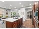 Open-concept kitchen with a large island, wooden cabinets, hardwood floors, and views into the living and office spaces at 5984 S Paris Pl, Greenwood Village, CO 80111
