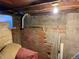 Unfinished basement with concrete and brick walls, storage, and some damaged wall at 1000 Denver Ave, Fort Lupton, CO 80621