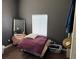Bedroom with dark gray walls, wood floors, stack of bedding, mirror and a window at 1000 Denver Ave, Fort Lupton, CO 80621