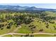 An aerial view of the home and property set among rolling hills and mature trees at 33448 Alta Vista Dr, Evergreen, CO 80439