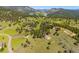 Aerial view of the home set amongst rolling hills, trees, and neighboring properties at 33448 Alta Vista Dr, Evergreen, CO 80439