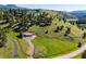 Aerial view of property, barn and home among rolling hills and mature trees at 33448 Alta Vista Dr, Evergreen, CO 80439
