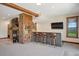 Open bar area featuring wooden cabinets, a marble countertop, and additional entertainment space near the fireplace at 33448 Alta Vista Dr, Evergreen, CO 80439
