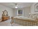 Carpeted bedroom with a bed with patterned quilt, an antique vanity, and a large window with curtains at 18470 Canterbury Dr, Monument, CO 80132