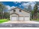 Three-car garage with ample parking space surrounded by mature trees and landscaping at 18470 Canterbury Dr, Monument, CO 80132
