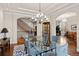 Formal dining room with a glass table, chandelier and a staircase in the background at 1160 Monaco Pkwy, Denver, CO 80220