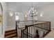 Upstairs hallway featuring a staircase with rod iron railing and large, decorative light fixture at 1160 Monaco Pkwy, Denver, CO 80220