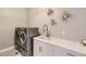 Modern laundry room featuring updated washer and dryer, sink, and cabinet with gold pulls at 6058 Beeler Ct, Denver, CO 80238