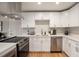 Modern kitchen featuring white cabinets, stainless steel appliances, quartz countertops, and hardwood floors at 12292 W 65Th Ave, Arvada, CO 80004