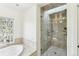 Bright bathroom with a glass-enclosed shower, soaking tub, a tile surround, and a window at 1919 Bellaire St, Denver, CO 80220