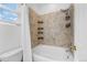 Tiled bathroom with an extendable shower head, mounted shelves, and a white tub at 13028 Grant W Cir # A, Thornton, CO 80241