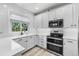 Bright kitchen with white cabinets, stainless steel appliances, and a window overlooking greenery at 13028 Grant W Cir # A, Thornton, CO 80241