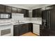 Dark wood kitchen cabinets, stainless steel appliances, and double sink at 5154 E 126Th Ct, Thornton, CO 80241