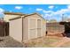 Tan colored storage shed in backyard with double doors at 5154 E 126Th Ct, Thornton, CO 80241