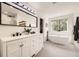 Bright bathroom featuring a double vanity, large tub and walk-in shower with marble tiling at 12693 W 82Nd Ln, Arvada, CO 80005