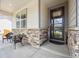 Cozy front porch seating area with stone accents and a stylish front door with glass, creating a welcoming entrance at 14670 Guernsey Dr, Mead, CO 80542