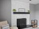 Close up of a white brick fireplace with wooden mantel and hearth in a gray living room at 18093 E Milan Pl, Aurora, CO 80013
