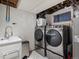Well lit laundry room with front loading washer and dryer, utility sink, and modern fixtures at 18093 E Milan Pl, Aurora, CO 80013