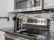 Close-up of kitchen with stainless steel range and mosaic tile backsplash at 18093 E Milan Pl, Aurora, CO 80013