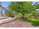 Spacious backyard with stone patio, lush greenery, large tree, and dining set at 1190 W 11Th Ct, Broomfield, CO 80020