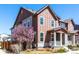 Inviting two-story home featuring a covered porch and a blossoming tree in the front yard at 8951 E 59Th Pl, Denver, CO 80238