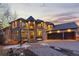Stunning stone house with three-car garage, basketball hoop, and manicured front yard, illuminated by twilight at 5810 Amber Ridge Dr, Castle Pines, CO 80108