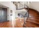 Grand foyer with curved staircase, hardwood floors, and views of the living room with a stone fireplace at 5810 Amber Ridge Dr, Castle Pines, CO 80108
