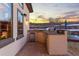 An outdoor kitchen equipped with a grill and mini-fridge, set against a scenic sunset at 5810 Amber Ridge Dr, Castle Pines, CO 80108