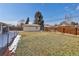 The backyard features well maintained grass, a detached garage, and partial snow coverage at 555 W Peakview Ave, Littleton, CO 80120